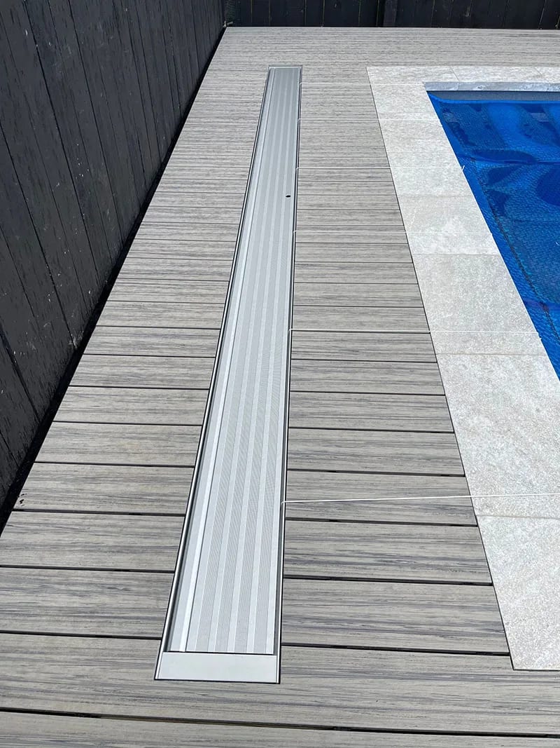 An in-ground cover, closed flush with the deck beside the pool
